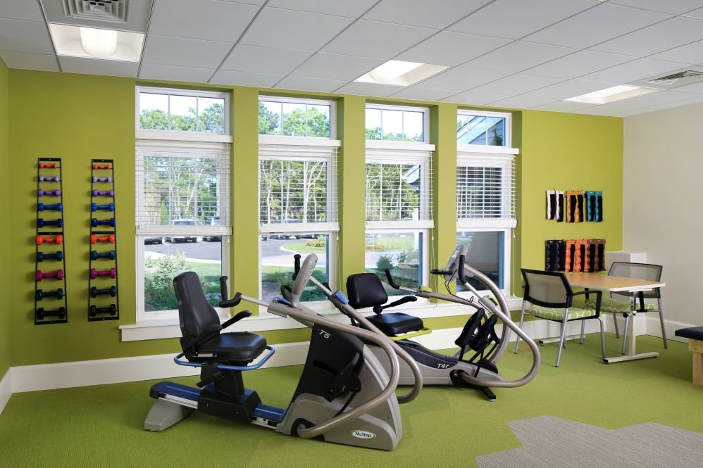 A modern fitness center with exercise equipment and large windows.