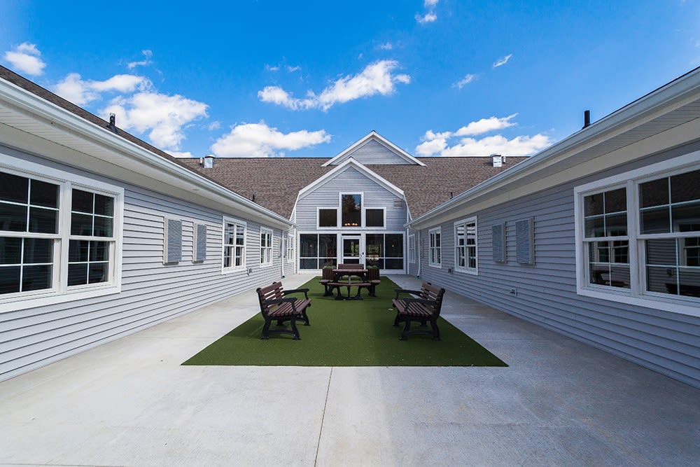 A courtyard with outdoor seating surrounded by a modern building under a blue sky.
