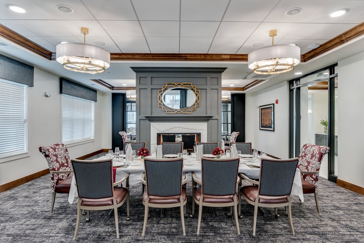 Elegant dining or conference room with a central table and chairs, featuring a fireplace and chandeliers.