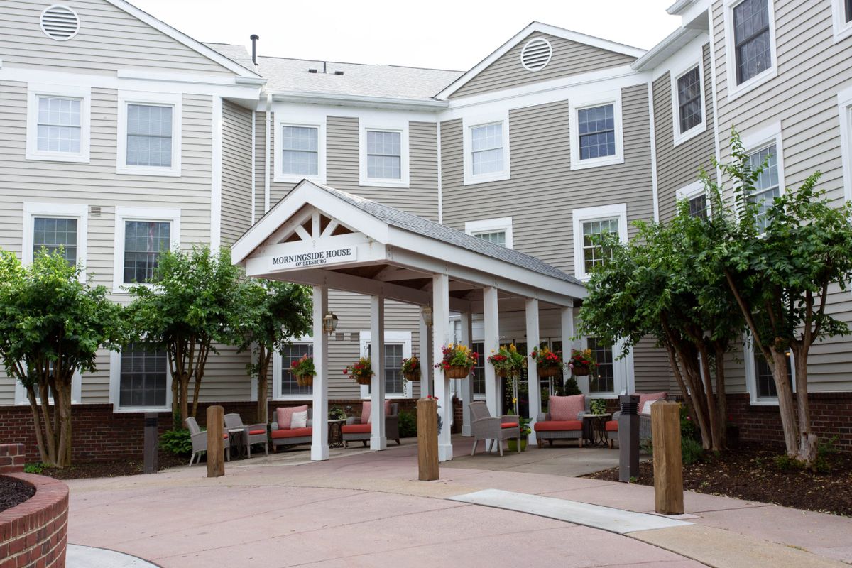 A residential building with a welcoming porch entrance surrounded by trees.