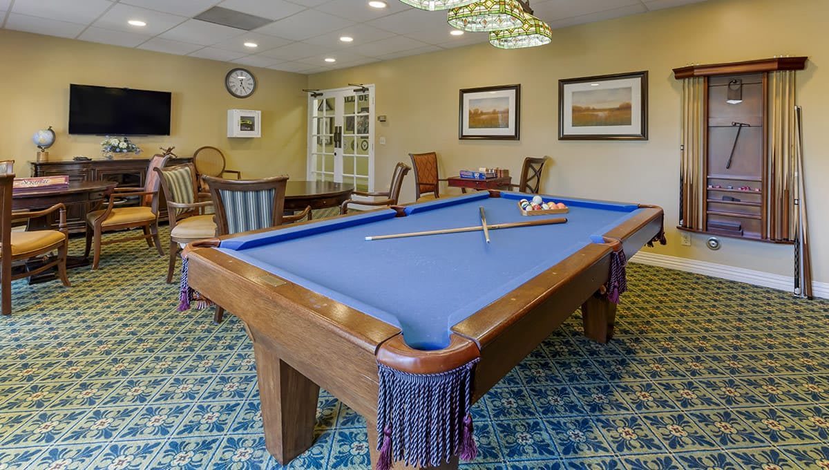 A cozy game room featuring a blue pool table surrounded by elegant furniture and decor.