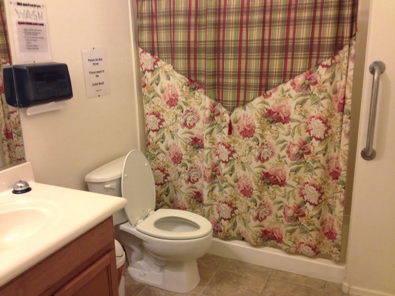 A bathroom with a floral and plaid shower curtain, toilet, and sink.