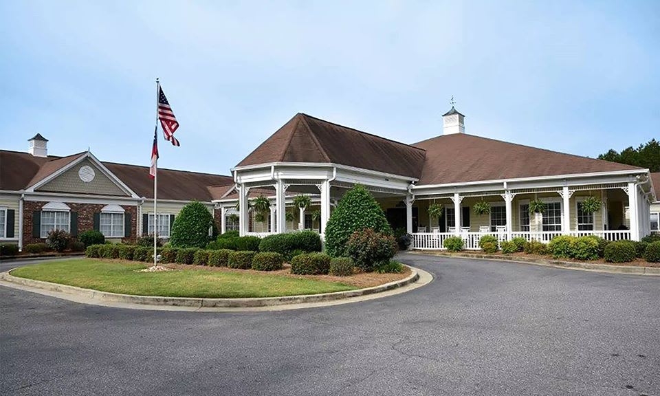A well-maintained building with a circular driveway, surrounded by landscaped gardens and featuring an American flag.
