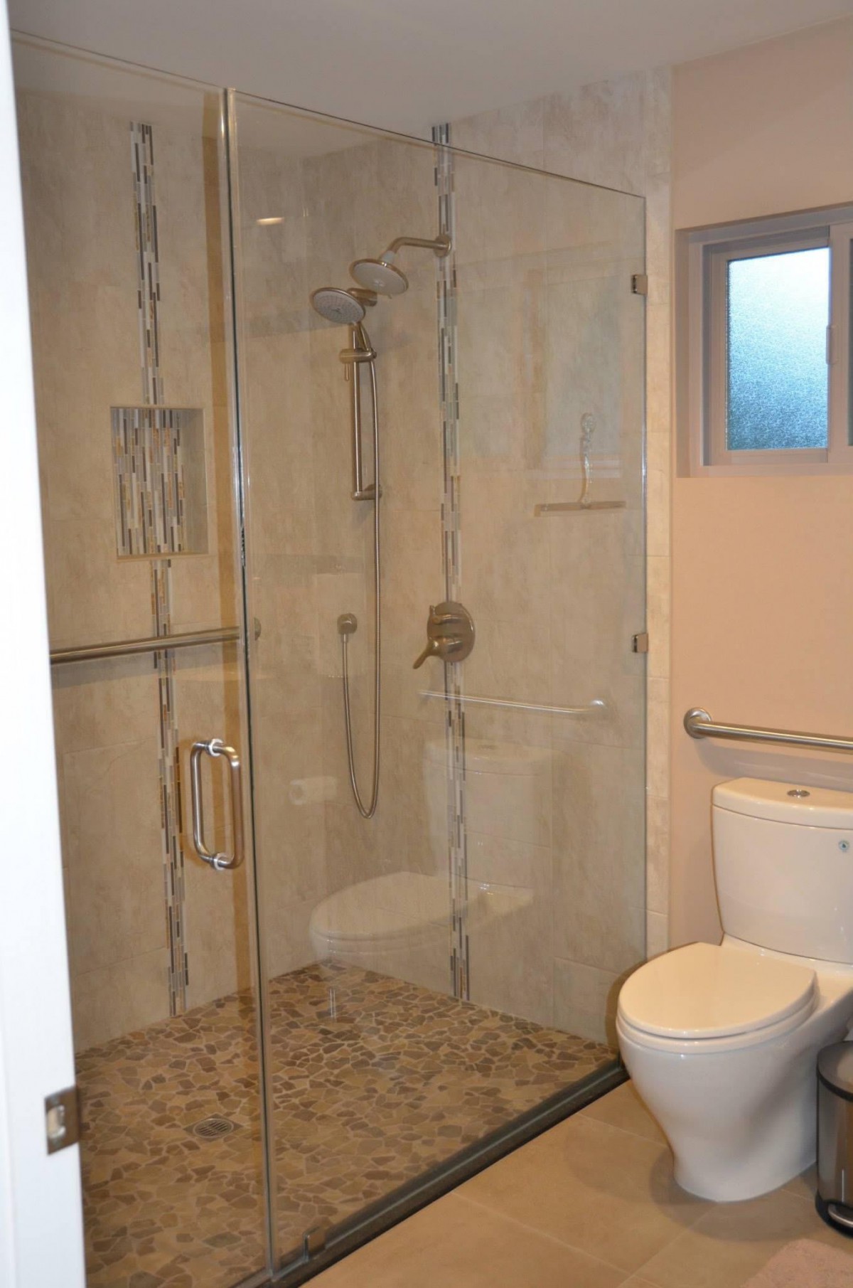 A modern bathroom with a glass-enclosed shower and toilet.