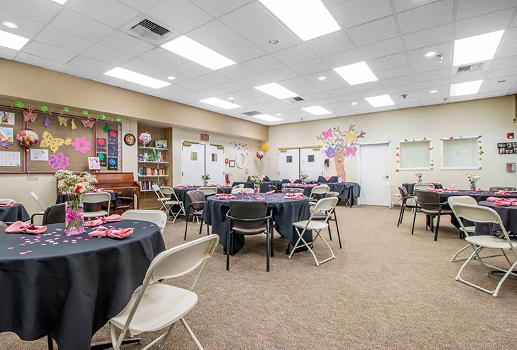 A decorated event space with tables and chairs arranged for a gathering.