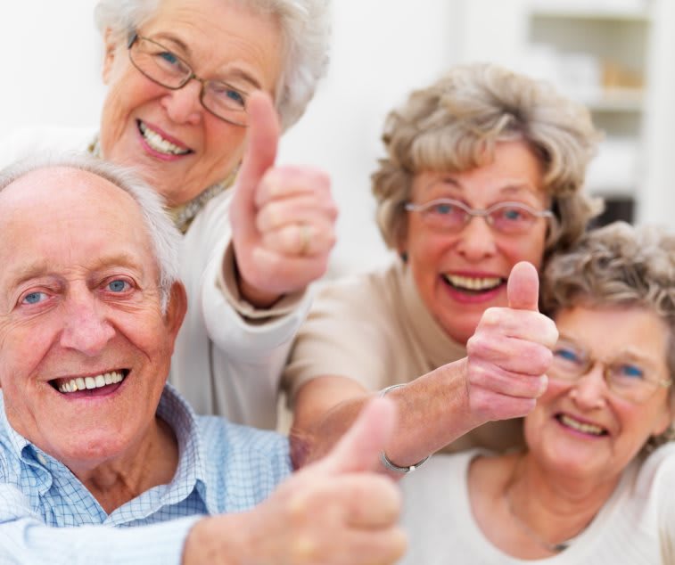 A group of happy seniors giving thumbs up.