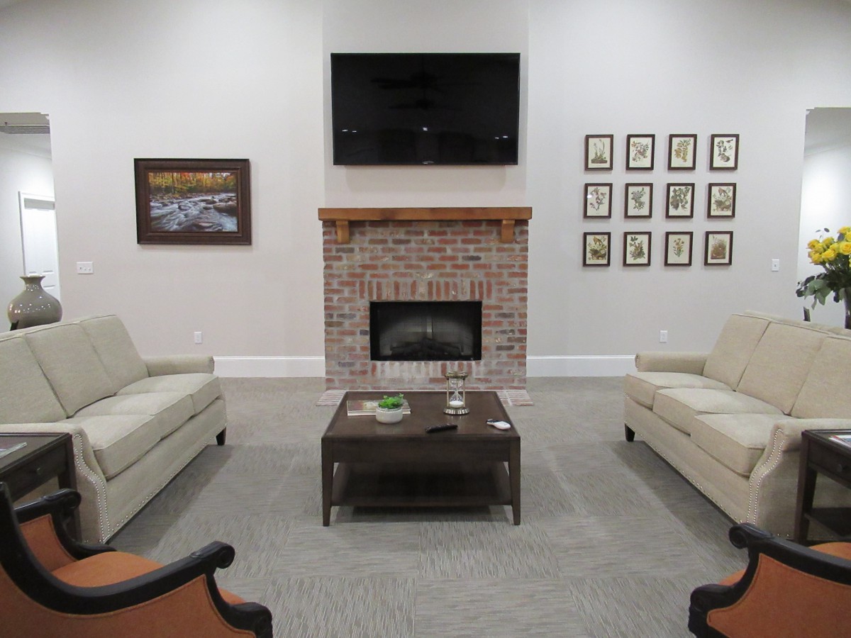 A cozy living room with a brick fireplace, two sofas, and a TV mounted above.