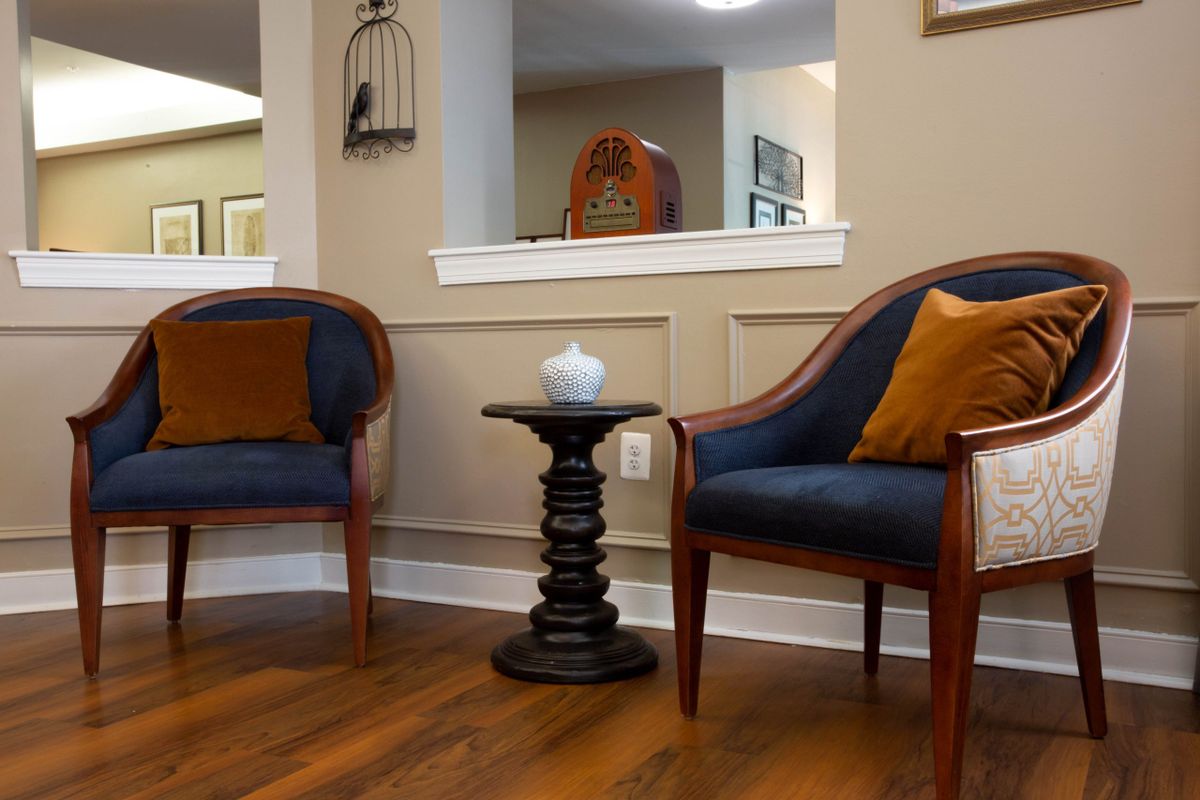 A cozy waiting room with two upholstered chairs, a small round table, and a decorative vase.