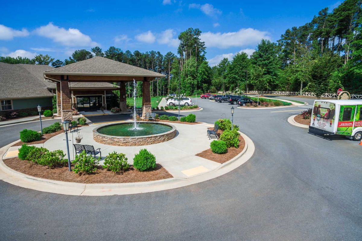 A scenic entrance with a roundabout featuring a fountain and surrounding greenery.