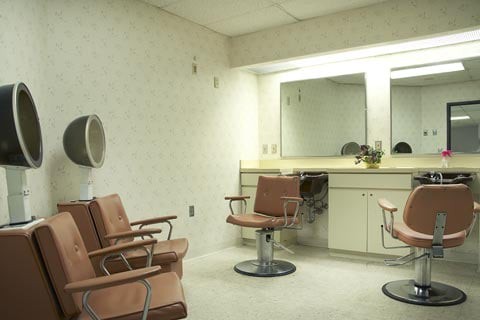 An empty salon with vintage chairs facing a large mirror.