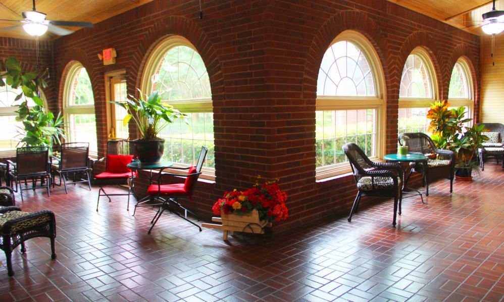 A cozy indoor seating area with brick walls, arched windows, and plants.