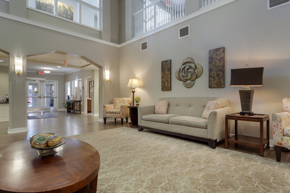 A spacious living room with elegant decor, featuring a sofa, armchairs, decorative artwork on the wall, and soft lighting.