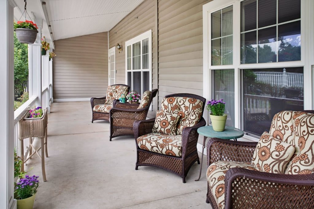 A cozy porch with wicker chairs, colorful cushions, and potted plants.