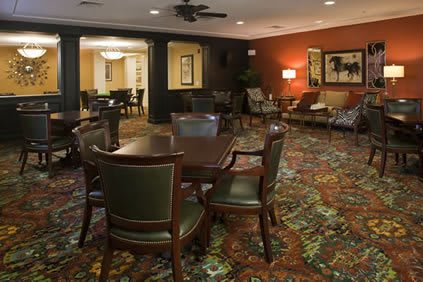 A cozy lounge area with chairs and a table, featuring warm lighting and a patterned carpet.