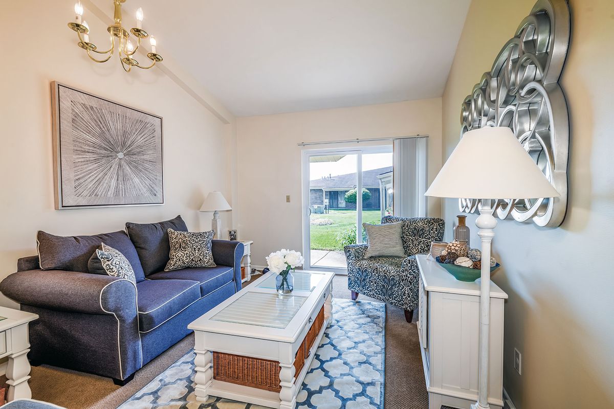 A cozy living room with a blue sofa, patterned armchair, and bright decor.