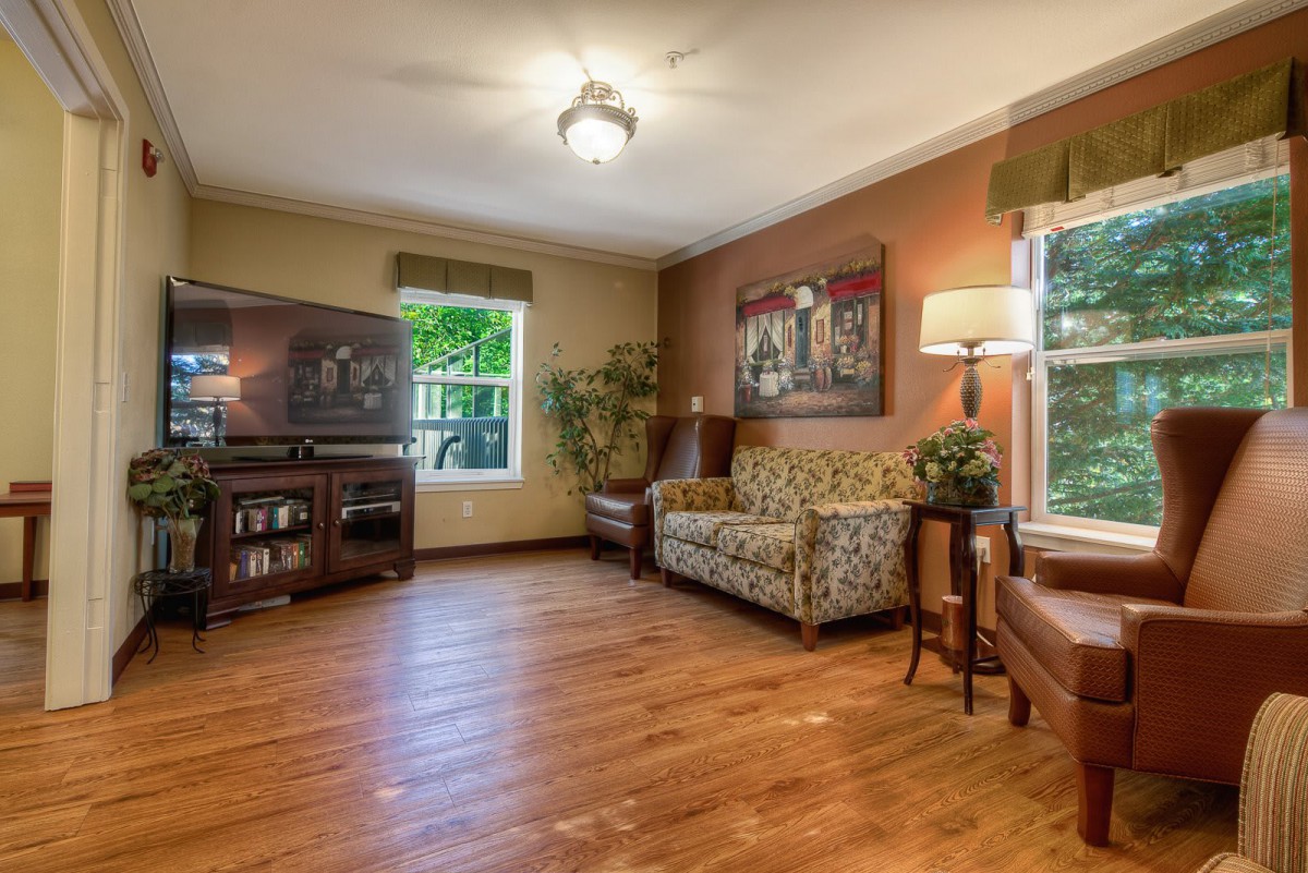 A cozy living room featuring a floral sofa, armchair, and hardwood flooring.