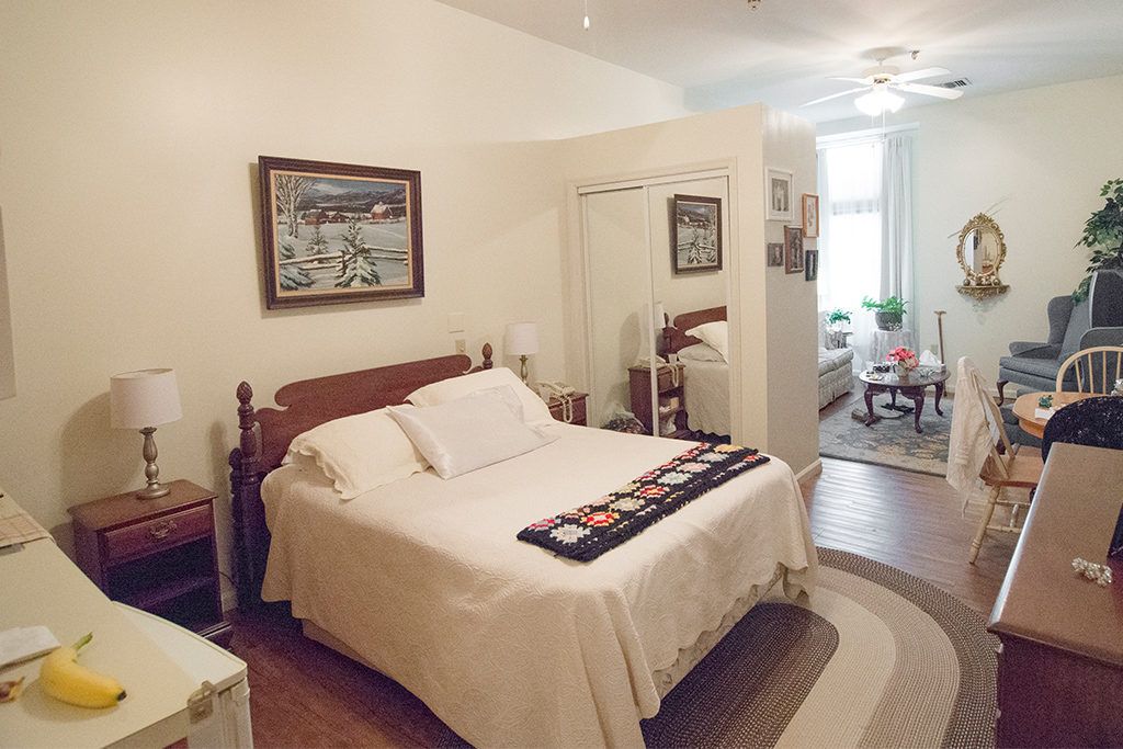 A cozy bedroom with a neatly made bed, mirror, and simple decor.