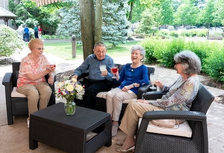 A group of seniors enjoying a social gathering outdoors with drinks in hand.