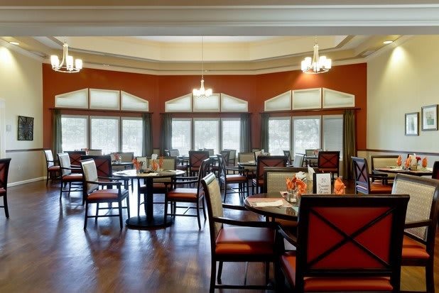 A spacious and well-lit dining area with multiple tables and chairs arranged neatly.