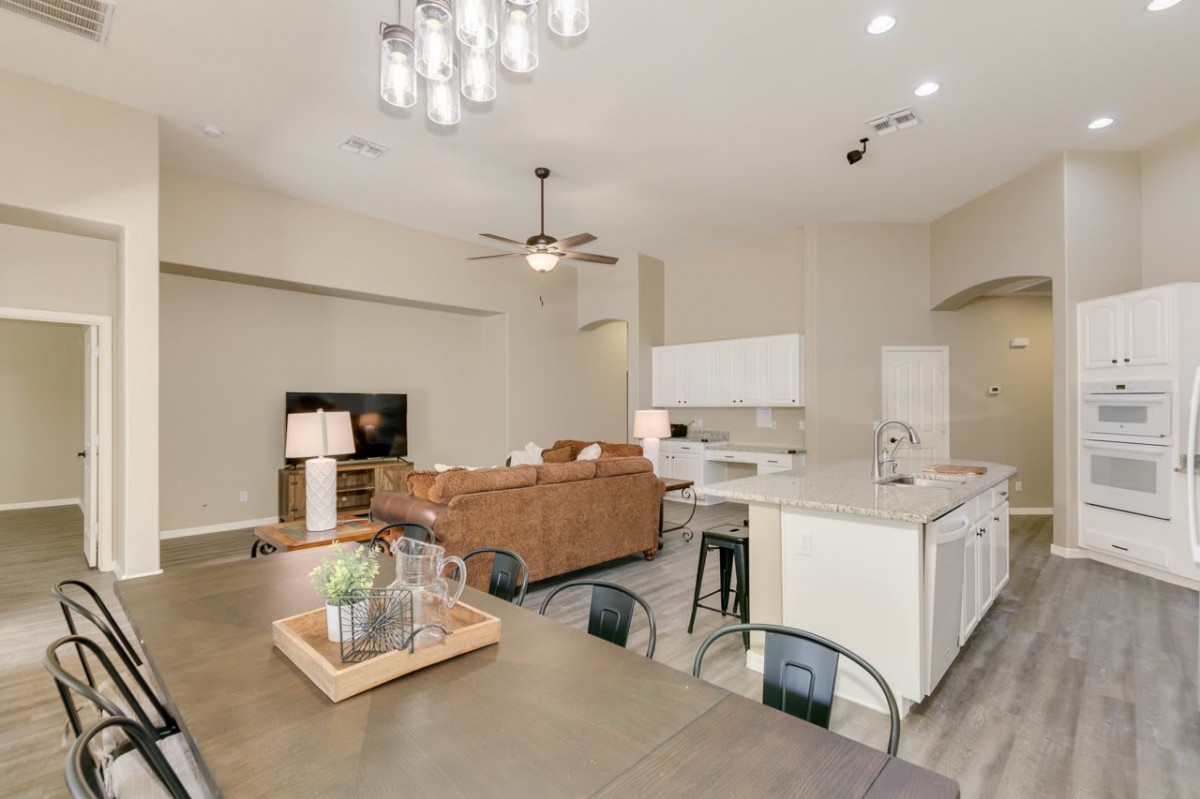 A modern open-concept living space featuring a kitchen, dining area, and comfortable living room with neutral tones.