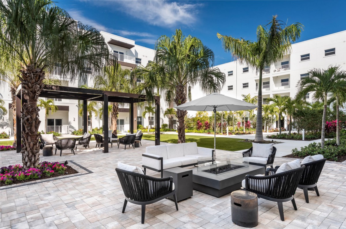 A luxurious outdoor patio with modern furniture and palm trees, perfect for relaxation on a sunny day.