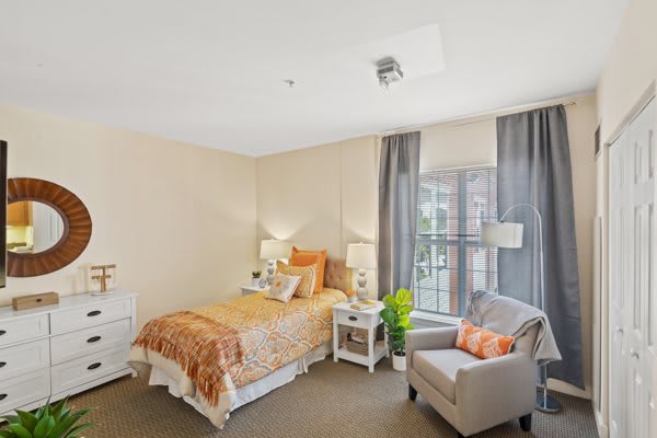 A cozy and modern bedroom with a single bed, armchair, and ample natural light.
