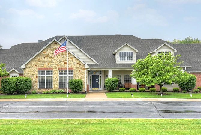 A suburban brick house with a well-maintained lawn and an American flag displayed.