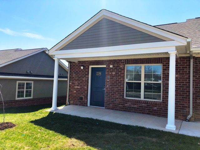 A brick house with a front porch under a clear blue sky.