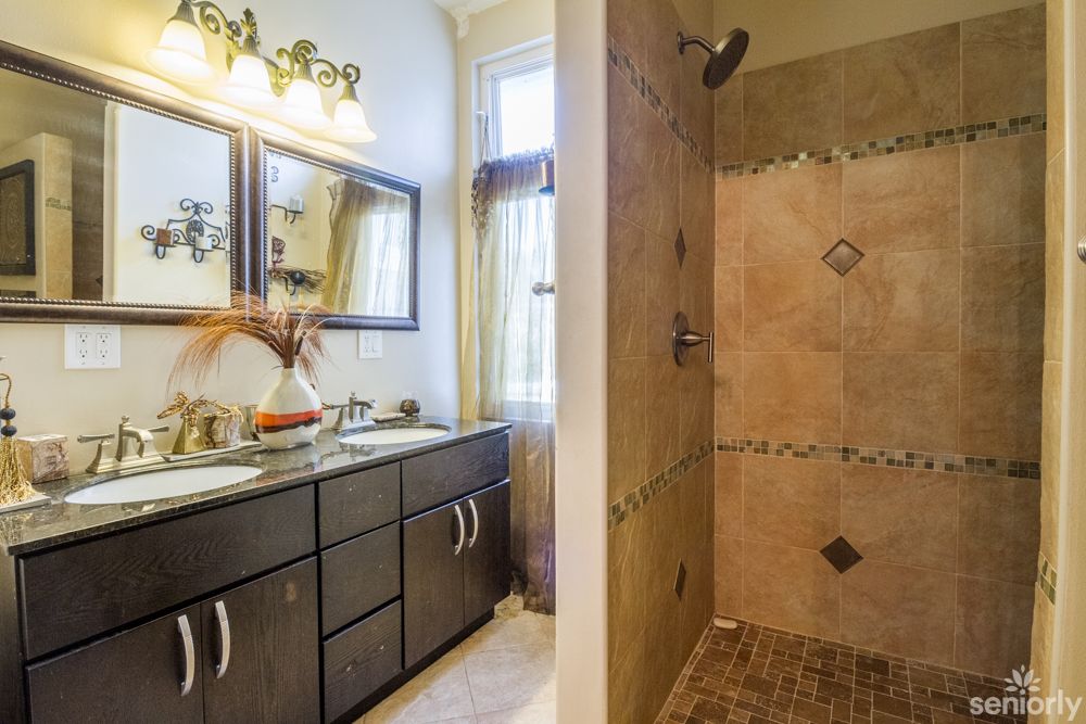 A modern bathroom featuring a double sink vanity and a tiled walk-in shower.