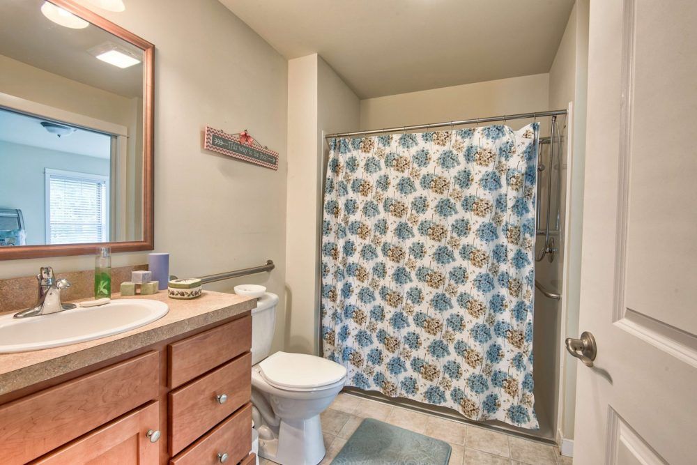 A clean and tidy bathroom with a decorative shower curtain and wooden vanity.