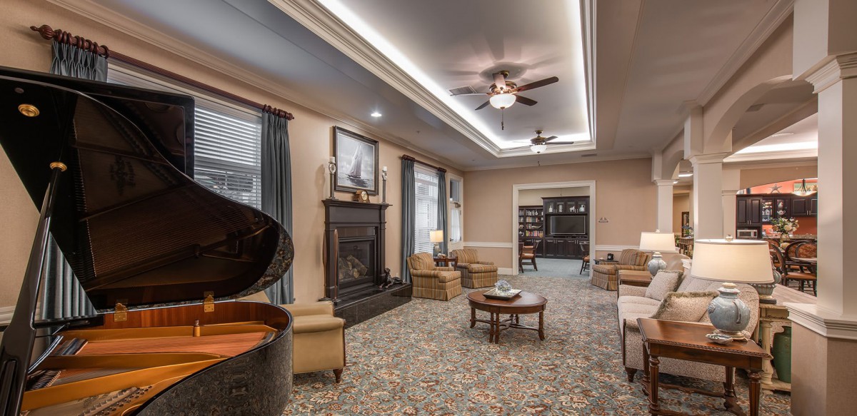 A cozy living room with elegant furnishings, including a grand piano and a fireplace.