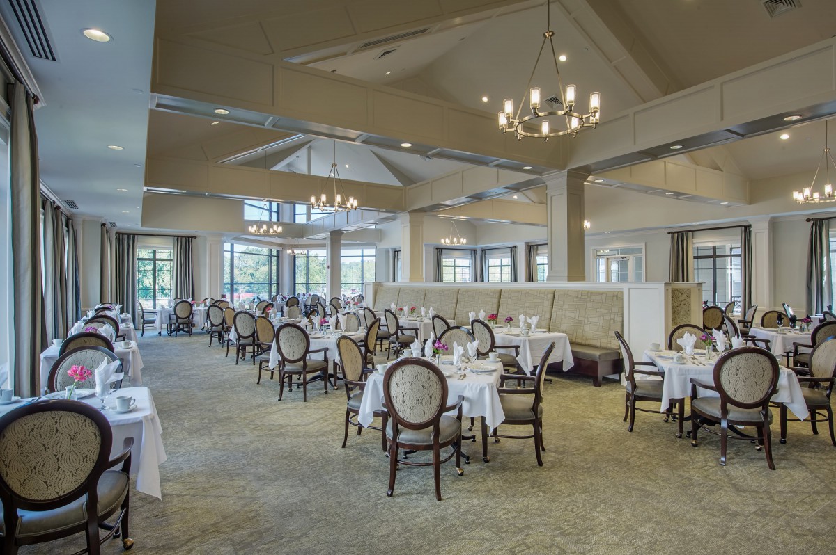 An elegant restaurant dining area with neatly arranged tables and chairs, illuminated by a chandelier.