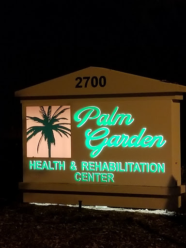 Illuminated sign for Palm Garden Health & Rehabilitation Center at night.