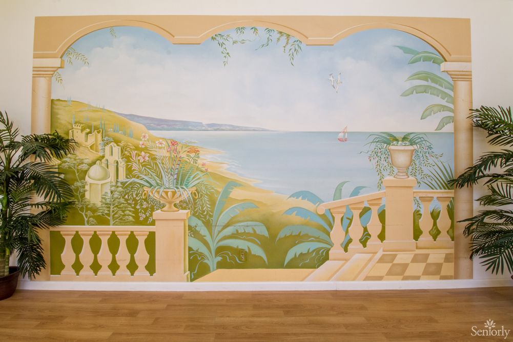 A mural depicting a scenic seaside view from a balcony with lush greenery.
