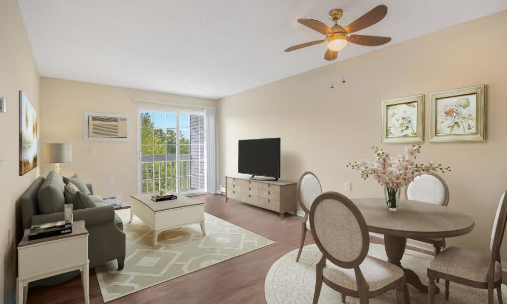 A spacious living room with modern furniture, featuring a sofa, table with chairs, television, and decor elements.