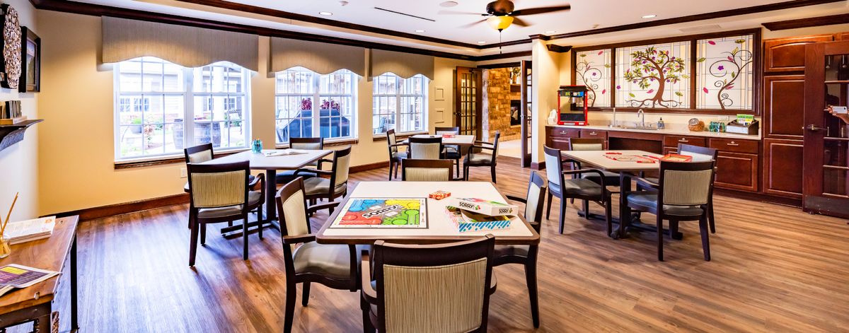 A well-lit community room with tables and chairs set up for board games.