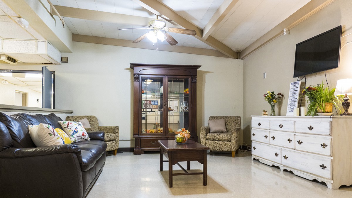 A cozy living room with a sofa, armchairs, and a wooden cabinet.