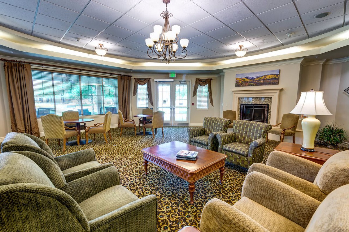 A cozy living room with armchairs, a central table, and a chandelier overhead.