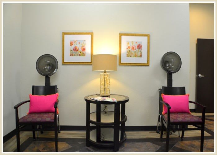 A cozy salon waiting area with chairs, hair dryers, and warm lighting.