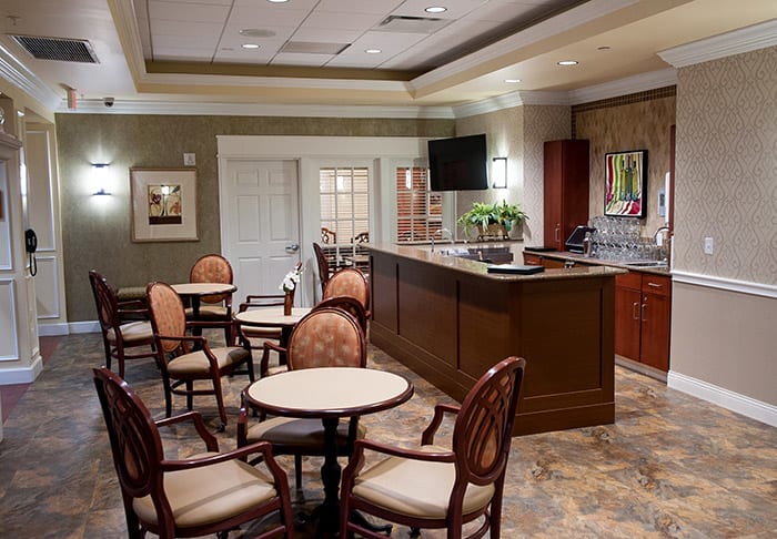 A cozy cafe interior with round tables and cushioned chairs, featuring warm lighting and elegant decor.
