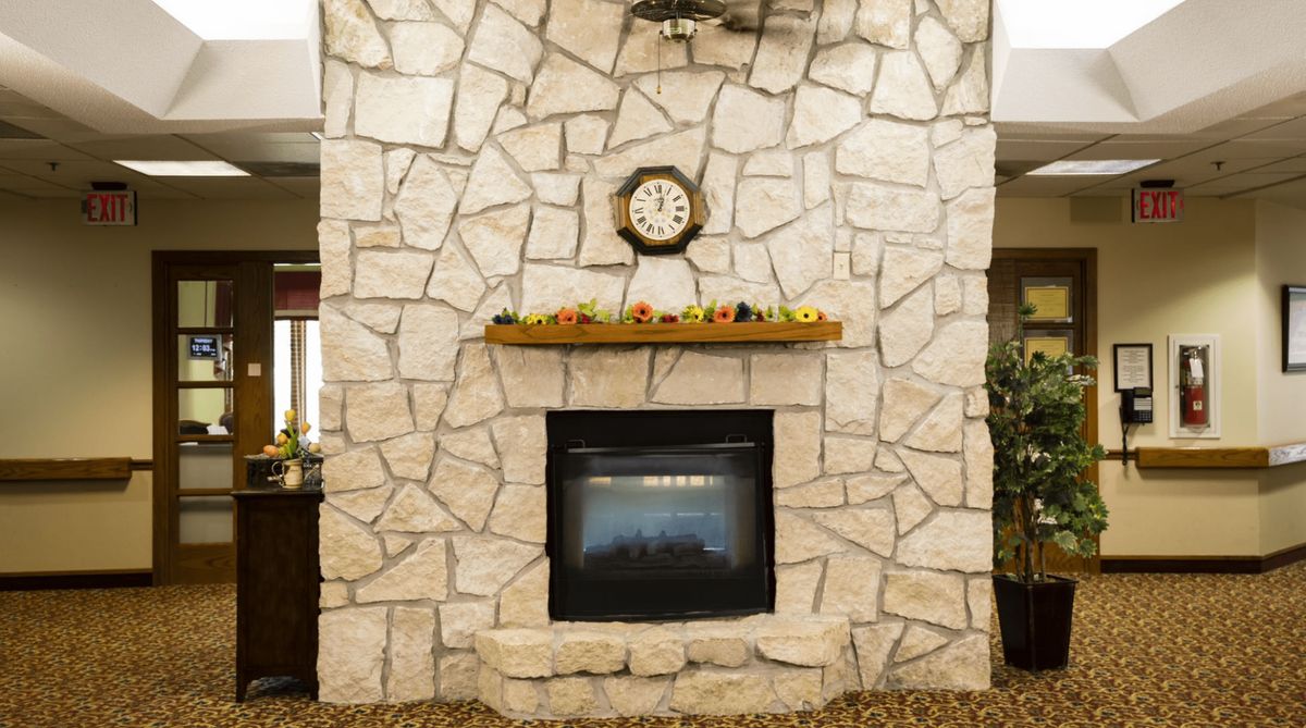 A stone fireplace with a clock and decorative items on the mantel.