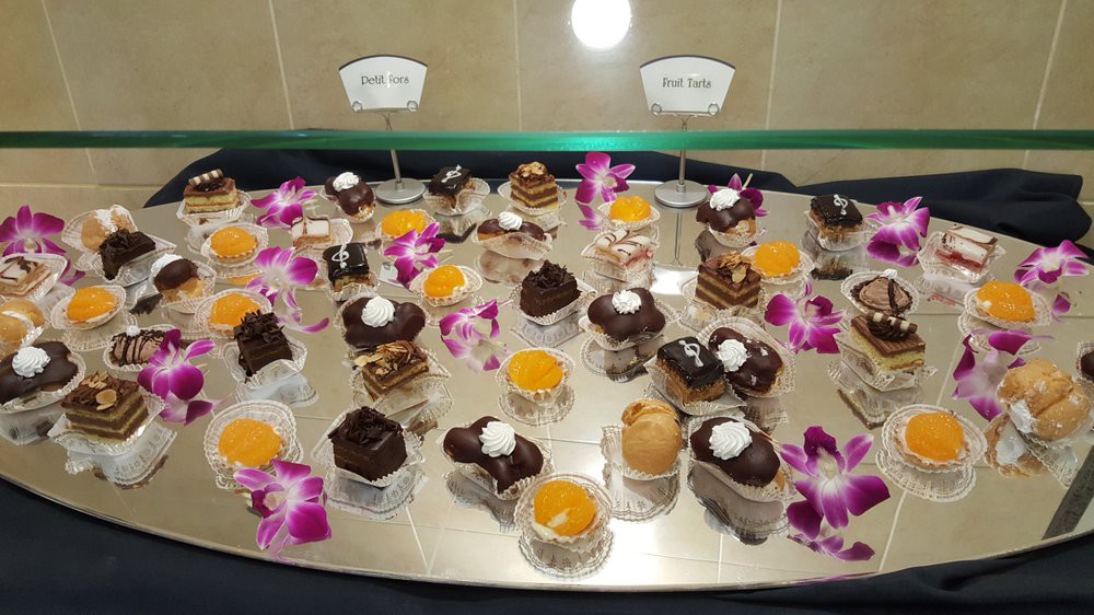 A beautifully arranged dessert display featuring an assortment of chocolate pastries and sweets, accented with colorful flowers.