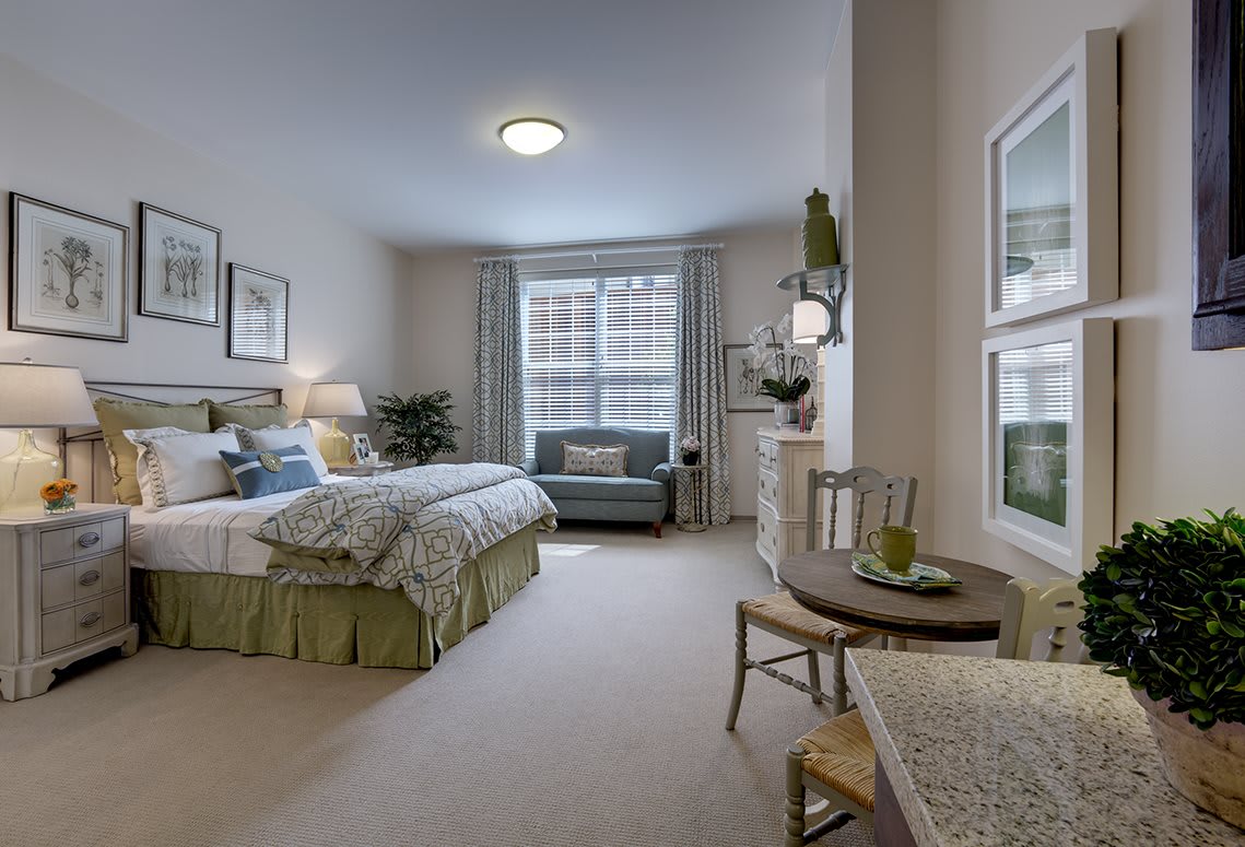 A cozy and well-decorated bedroom with a bed, seating area, and soft lighting.
