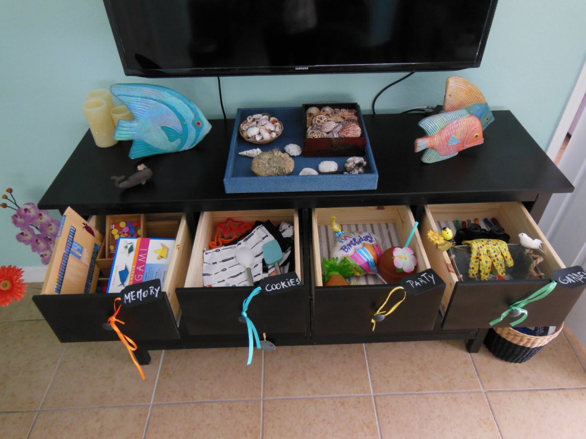 Organized storage bins under a TV, featuring labeled boxes for toys and crafts.