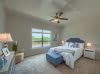 A modern bedroom with a large window, stylish decor, and a ceiling fan.