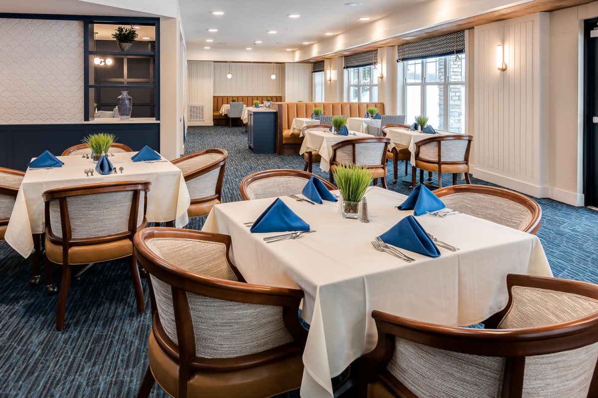 Elegant restaurant dining area with tables set for guests, featuring blue napkins and modern decor.