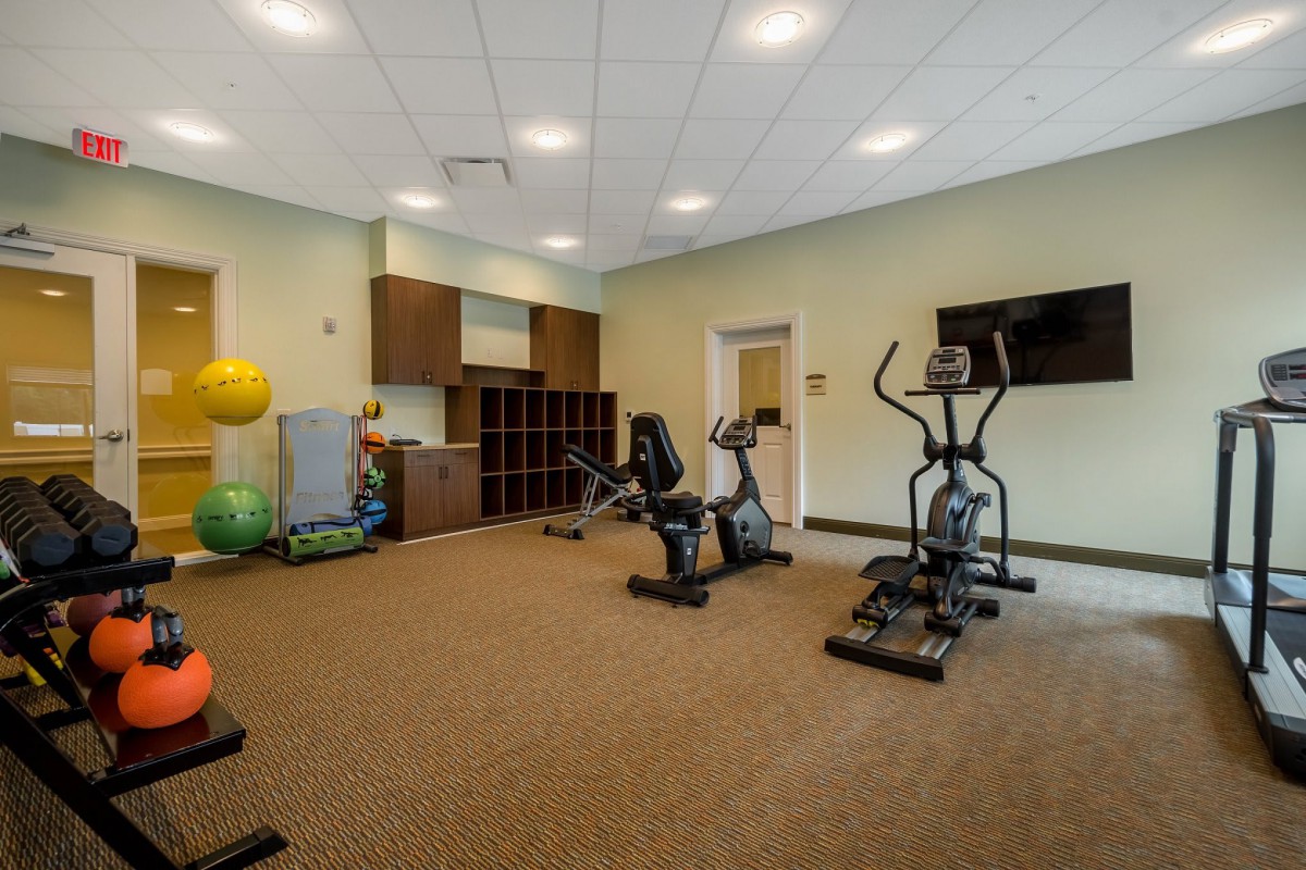 A well-equipped fitness room with cardio machines and exercise equipment.