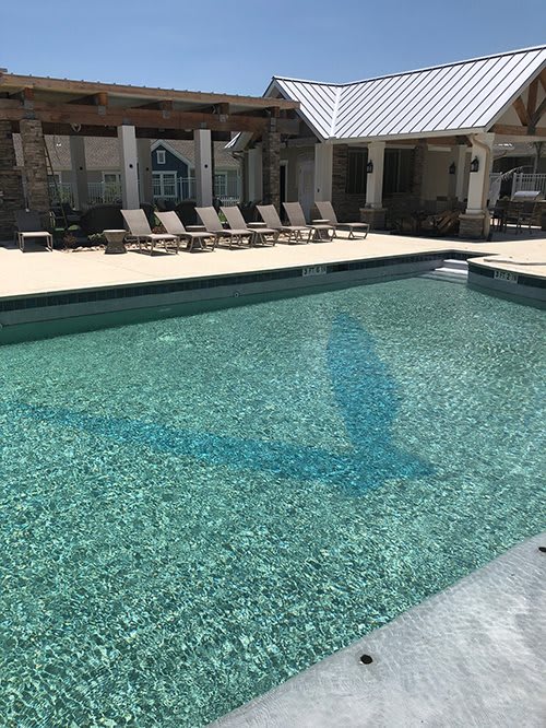 A serene outdoor swimming pool surrounded by lounge chairs, set in a sunny resort atmosphere.