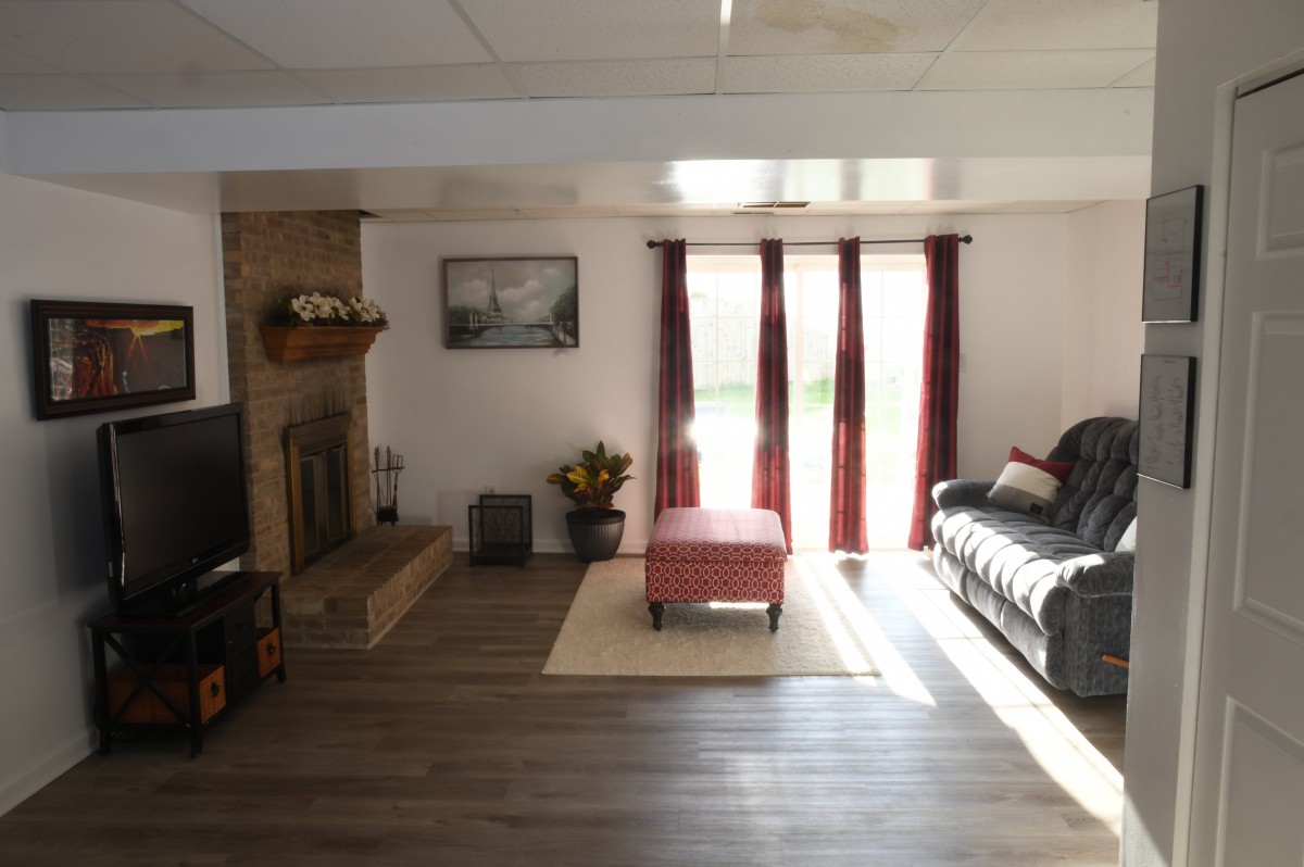 A cozy living room with a fireplace, red curtains, and ample natural light.