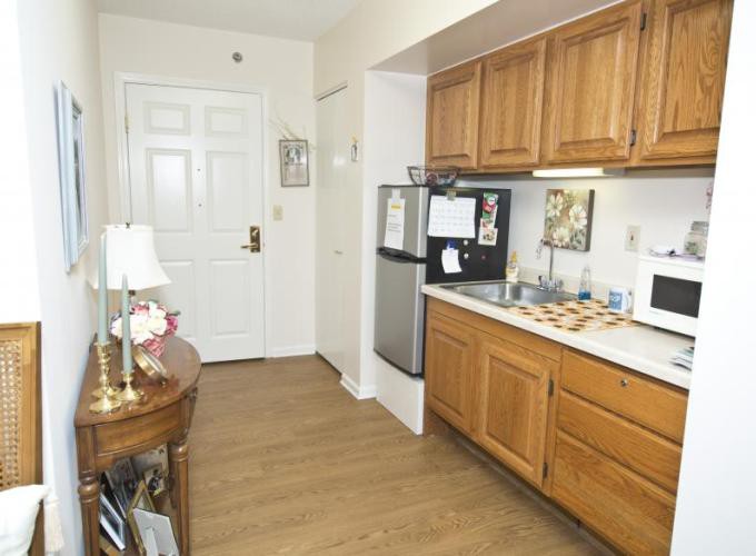 A cozy apartment kitchen with wooden cabinets and a small fridge.